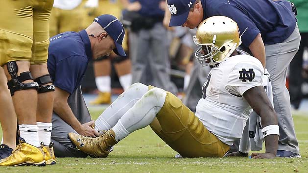 Sep 12, 2015; Charlottesville, VA, USA; Notre Dame Fighting Irish quarterback Malik Zaire (8) is examined by team trainers after injuring his right ankle against the Virginia Cavaliers in the third quarter at Scott Stadium. The Fighting Irish won 34-27. Mandatory Credit: Geoff Burke-USA TODAY Sports