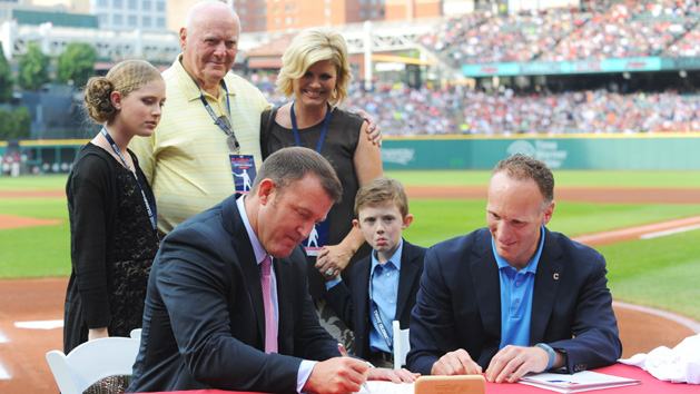 Aug 2, 2014; Cleveland, OH, USA; Surrounded by his family, Cleveland Indians former player Jim Thome signs a one-day contract with Cleveland Indians president Mark Shapiro before the game between the Cleveland Indians and the Texas Rangers at Progressive Field. Ken Blaze-USA TODAY Sports