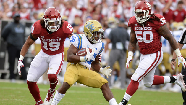 Sep 8, 2018; Norman, OK, USA; UCLA Bruins running back Martell Irby (26) runs against Oklahoma Sooners linebacker Caleb Kelly (19) and defensive tackle Arthur McGinnis (50) during the fourth quarter at Gaylord Family - Oklahoma Memorial Stadium. Photo Credit: Mark D. Smith-USA TODAY Sports