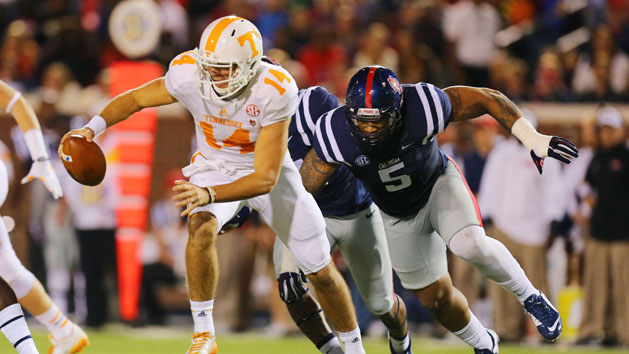 Oct 18, 2014; Oxford, MS, USA; Tennessee Volunteers quarterback Justin Worley (14) advances the ball while being chased by Mississippi Rebels defensive tackle Robert Nkemdiche (5) during the game at Vaught-Hemingway Stadium. Mandatory Credit: Spruce Derden-USA TODAY Sports