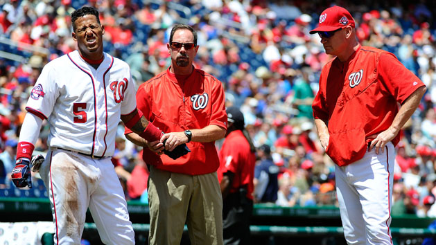 Jul 22, 2015; Washington, DC, USA; Washington Nationals third baseman Yunel Escobar (5) reacts as trainer Lee Kuntz exams his wrist as manager Matt Williams (9) looks on against the New York Mets during the second inning at Nationals Park. Mandatory Credit: Brad Mills-USA TODAY Sports