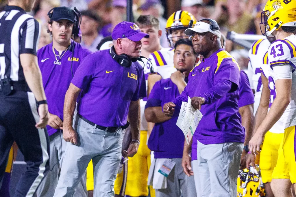 Former LSU Tigers head coach Brian Kelly (left) and current interim head coach Frank Wilson (right).